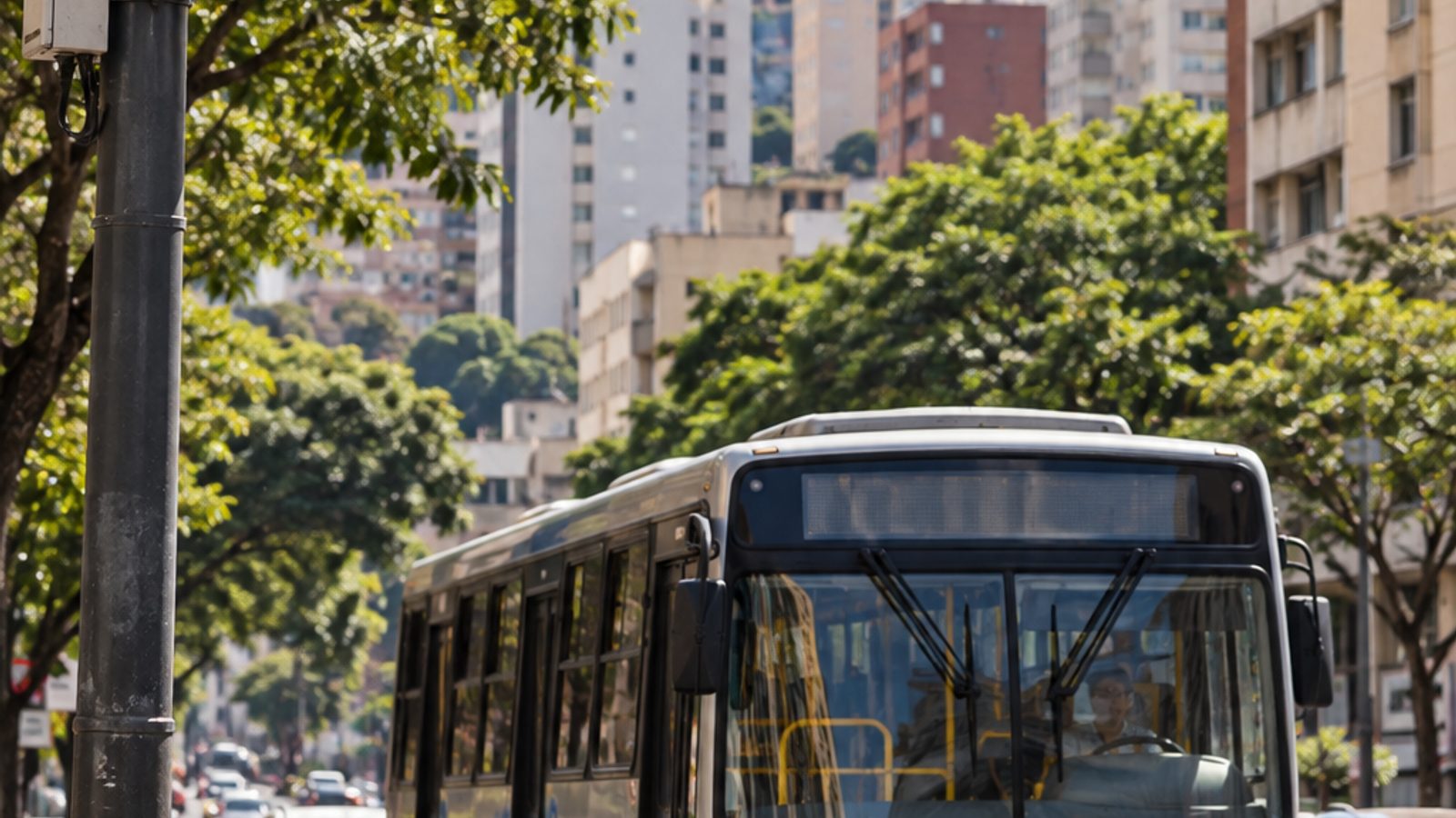 Imagem ilustrativa de ônibus e semáforo com câmera em corredor urbano brasileiro.